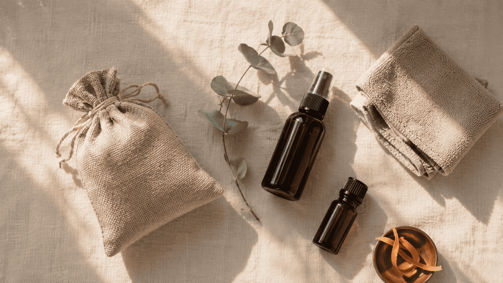 Charcoal bag, eucalyptus sprig, and a small spray bottle on cream linen — the natural maintenance kit